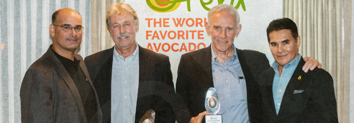 Four men pose at an Avocados from Peru event while two hold award plaques in front of a branded backdrop.