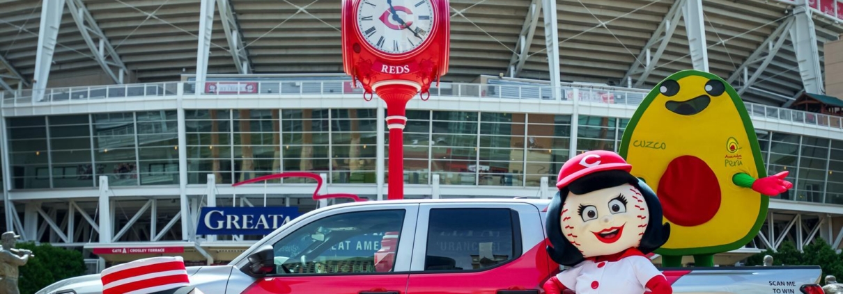 Avocados From Peru and Cincinnati Reds branded pickup truck with team mascots and an avocado mascot outside Great American Ball Park.